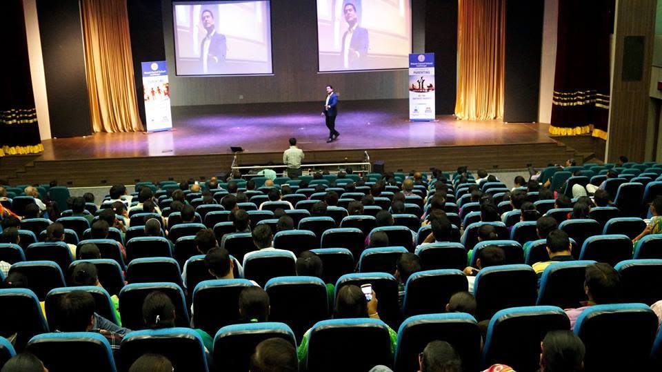 Parikshit Jobanputra parenting coach speaking on stage with his portrait on the screen